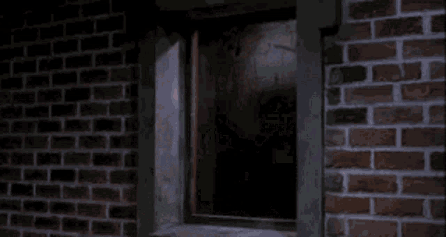a brick wall with a broken glass window and a spider coming out of it .