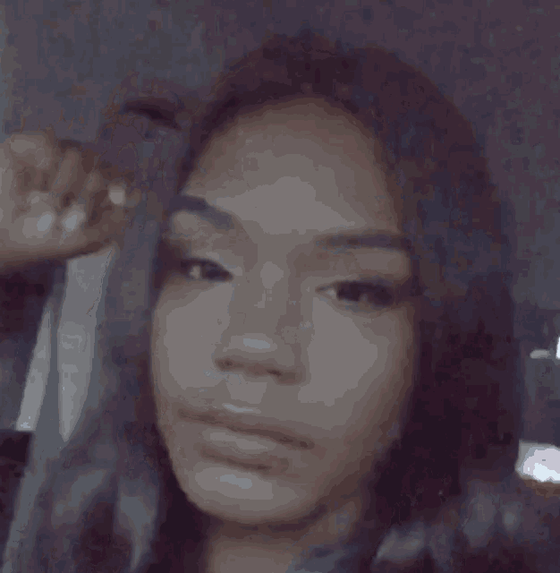 a close up of a woman 's face in a car with her hand on her head .