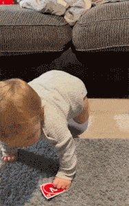 a baby is crawling on the floor with a playing card that says ' a ' on it