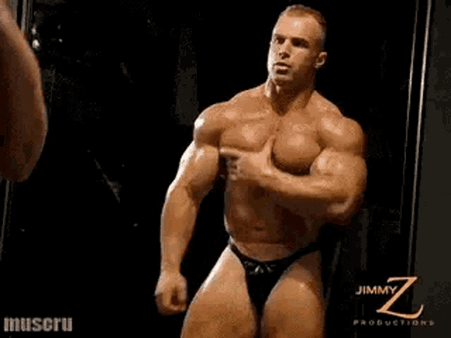 a muscular man is standing in front of a mirror in a gym .