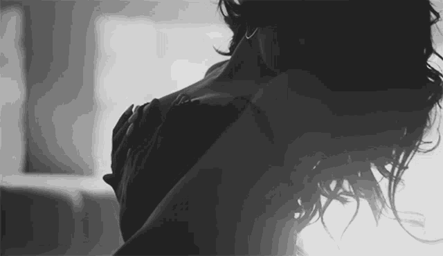 a black and white photo of a woman in lingerie holding her chest .