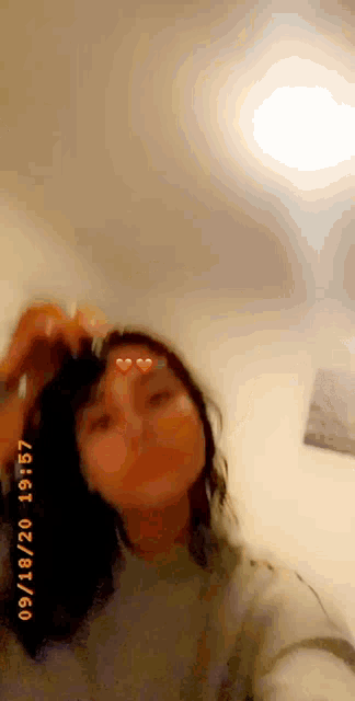 a woman is taking a selfie in a room with a heart on her face .