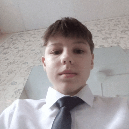 a young boy wearing a white shirt and black tie