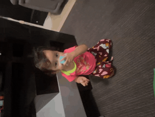 a little girl wearing a pink shirt with hearts on it
