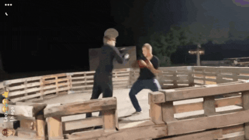 two men are boxing in front of a wooden fence with a time stamp of 4:20