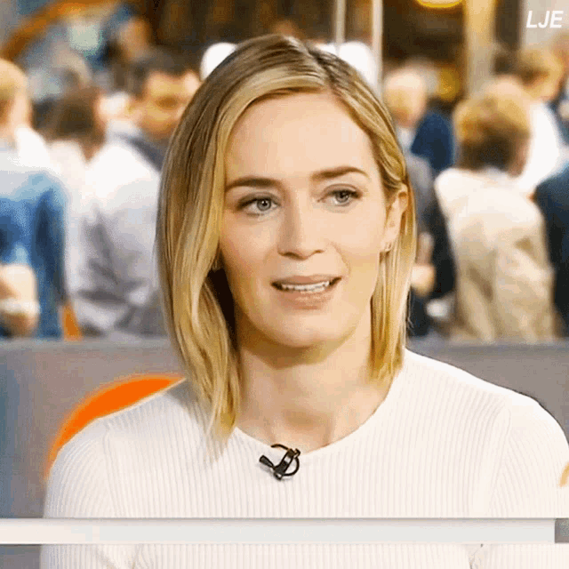 a woman wearing a white sweater and a microphone with the letters lje on the bottom left
