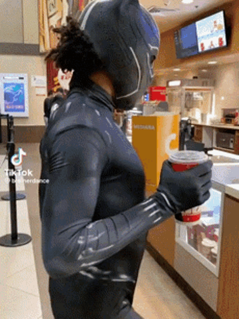 a man in a black panther costume holding a cup