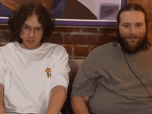 two men are sitting next to each other with one wearing a shirt that says ' a ' on the front