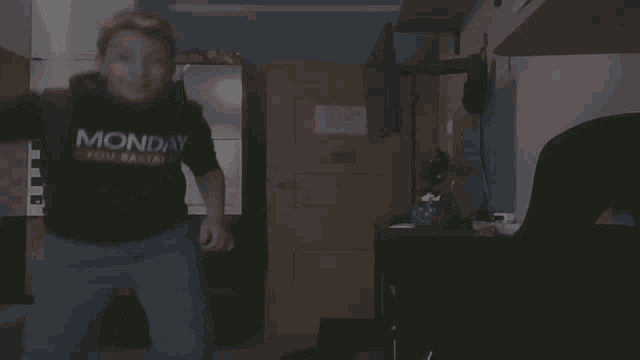 a person wearing a black monday shirt is dancing in a dark room