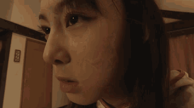 a close up of a woman 's face with a sign on the wall behind her