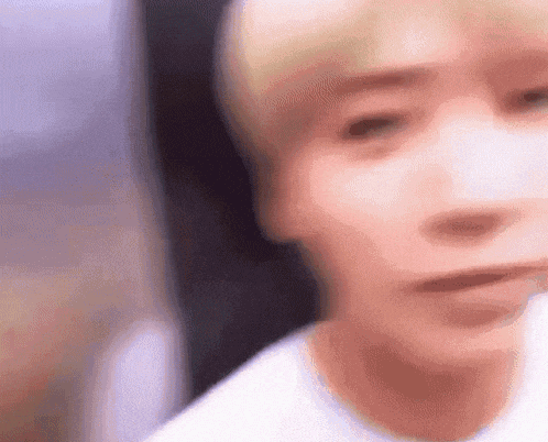 a close up of a person 's face with a blurry background and a white shirt on .