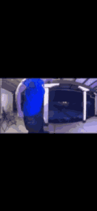 a blurry picture of a man in a blue shirt standing in front of a pool