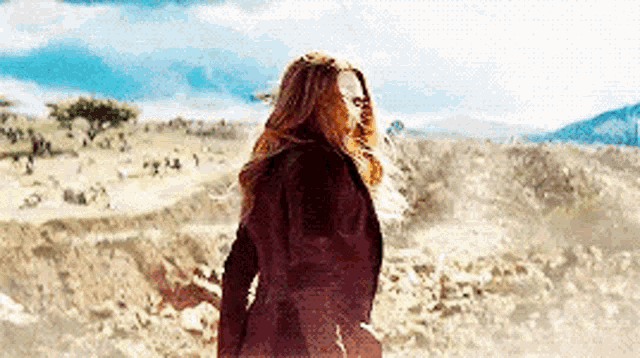 a woman in a black coat is standing in a field .