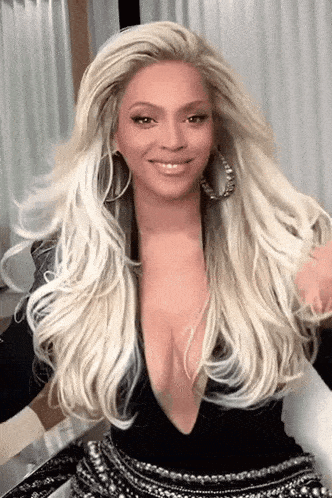 a woman with long blonde hair and a plunging neckline is wearing a black top and earrings .