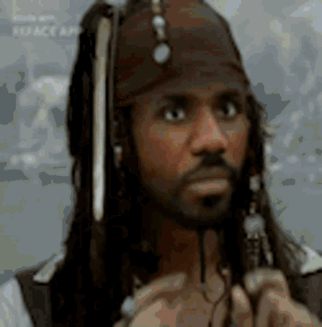a man with dreadlocks and a beard is wearing a bandana and headphones .