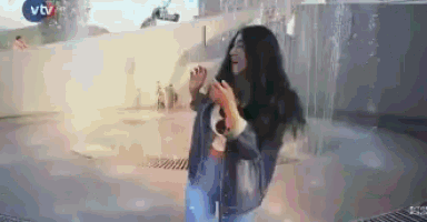 a woman with long black hair is standing in front of a vtv sign