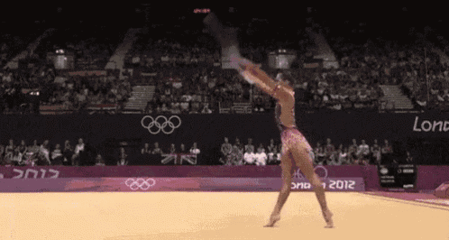 a female gymnast performs a trick in front of a crowd at the london olympics