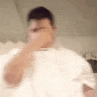 a blurry picture of a man covering his nose with his hand .