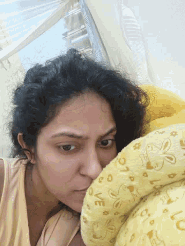 a woman laying on a bed with a yellow blanket that says ' love ' on it