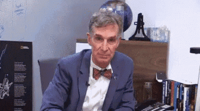 a man in a blue suit and bow tie is sitting at a desk in front of a globe .
