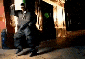 a man is dancing on a sidewalk in front of a building at night .