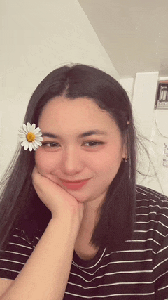 a woman wearing a striped shirt and a flower in her hair is smiling .