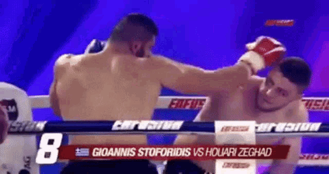 two men are fighting in a boxing ring on a television show .