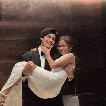 a man is carrying a woman in a white dress in an elevator