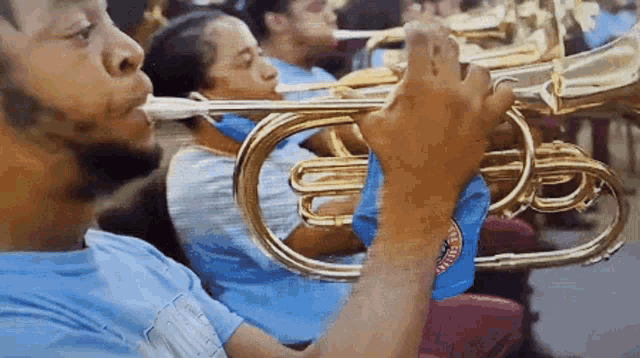 a man in a blue shirt is playing a trombone