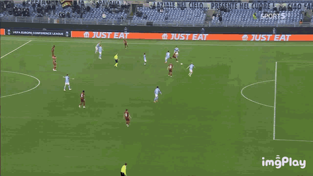 a soccer game is being played on a field with a just eat sign