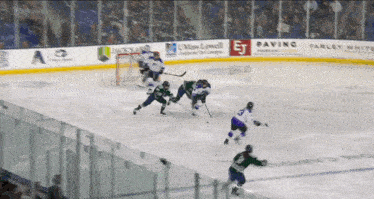 a hockey game is being played on a rink with ads for miss lowell paving and parley white