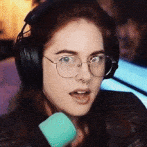 a woman wearing headphones and glasses holds a microphone