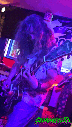 a picture of a man playing a guitar with the words grindhorses on the bottom right