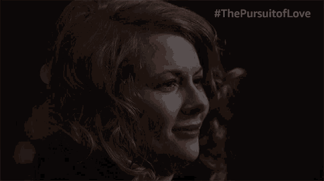 a woman is laughing in a dark room with the #thepursuitoflove written above her