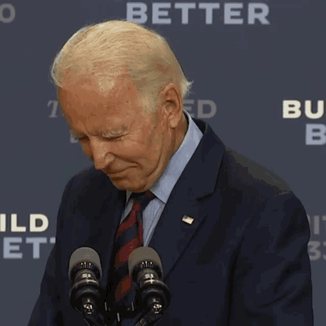 a man in a suit and tie stands in front of two microphones with the word better on the back