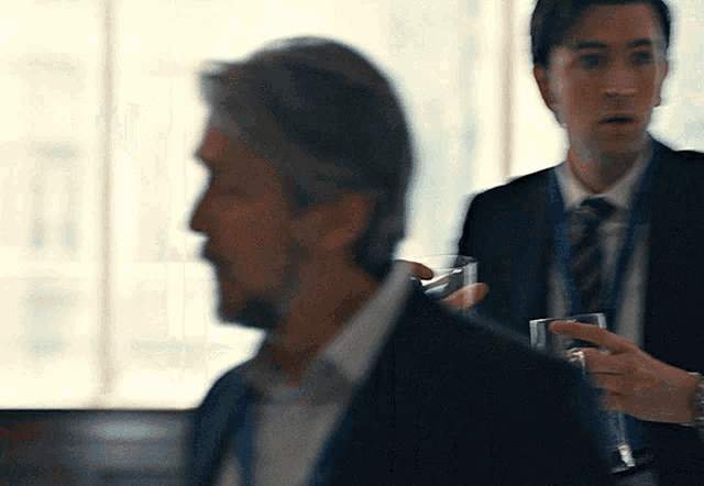 a man in a suit and tie holds a glass in his hand