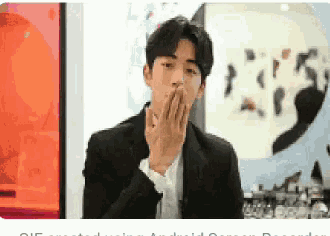 a man in a suit covering his mouth with his hands