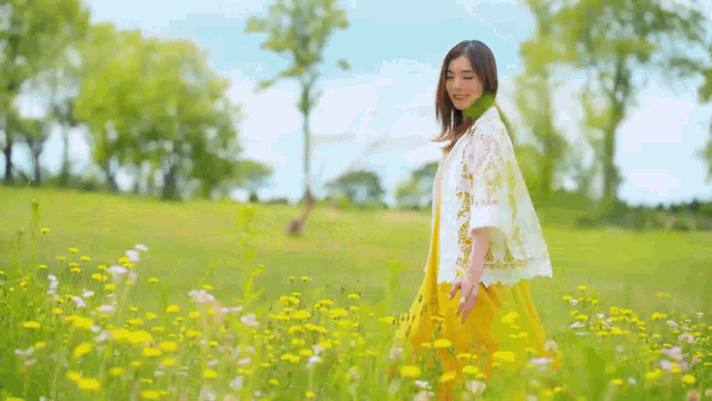 a woman in a yellow dress and white jacket is walking through a field of flowers .