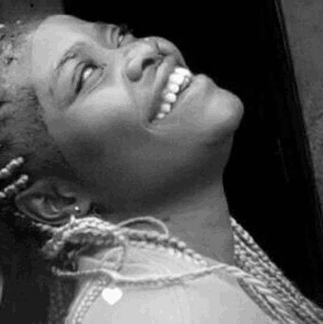 a woman is smiling in a black and white photo while looking up .