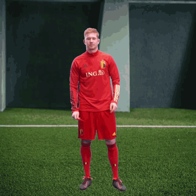 a man in a red ing jersey stands on a green field