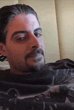 a man with a beard and mustache is wearing a black shirt with a picture of a man on it