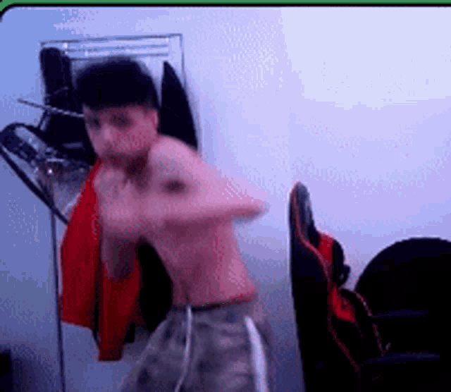 a shirtless man is standing in a room with a fan
