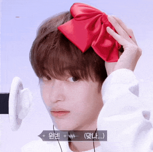 a person wearing a red bow on their head with korean writing on the bottom right