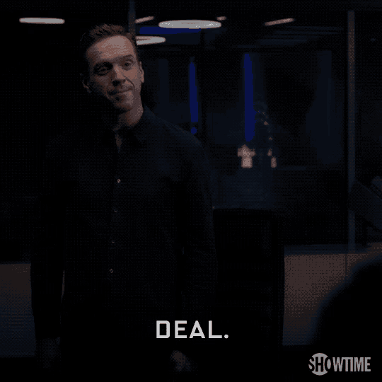 a man in a black shirt is standing in a dark room and says deal