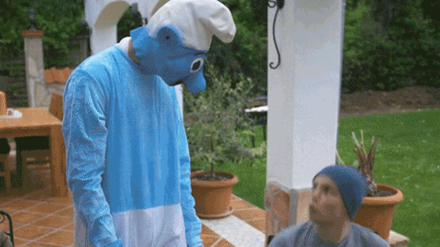 a man in a smurf costume stands next to a man in a beanie