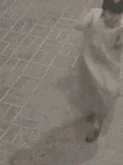 a person is squatting down on the ground on a brick sidewalk .