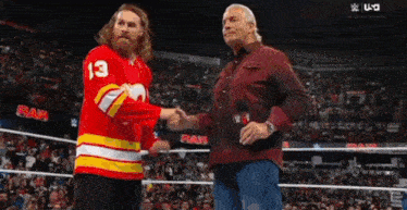 a man in a red jersey with the number 13 on it shakes hands with another man in a maroon shirt