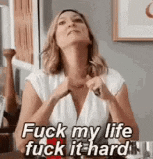 a woman is sitting at a table with her hands on her chest and says `` fuck my life , fuck it hard '' .