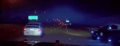 a police car is driving down a highway at night .