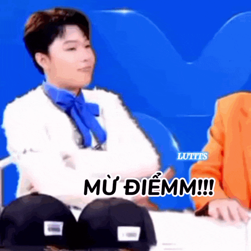a man wearing a white sweater and a blue bow tie is sitting next to another man .